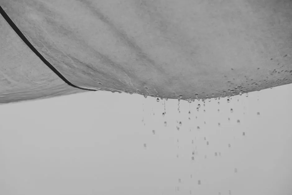 Black and white composition of water drops falling from rag material on gray background